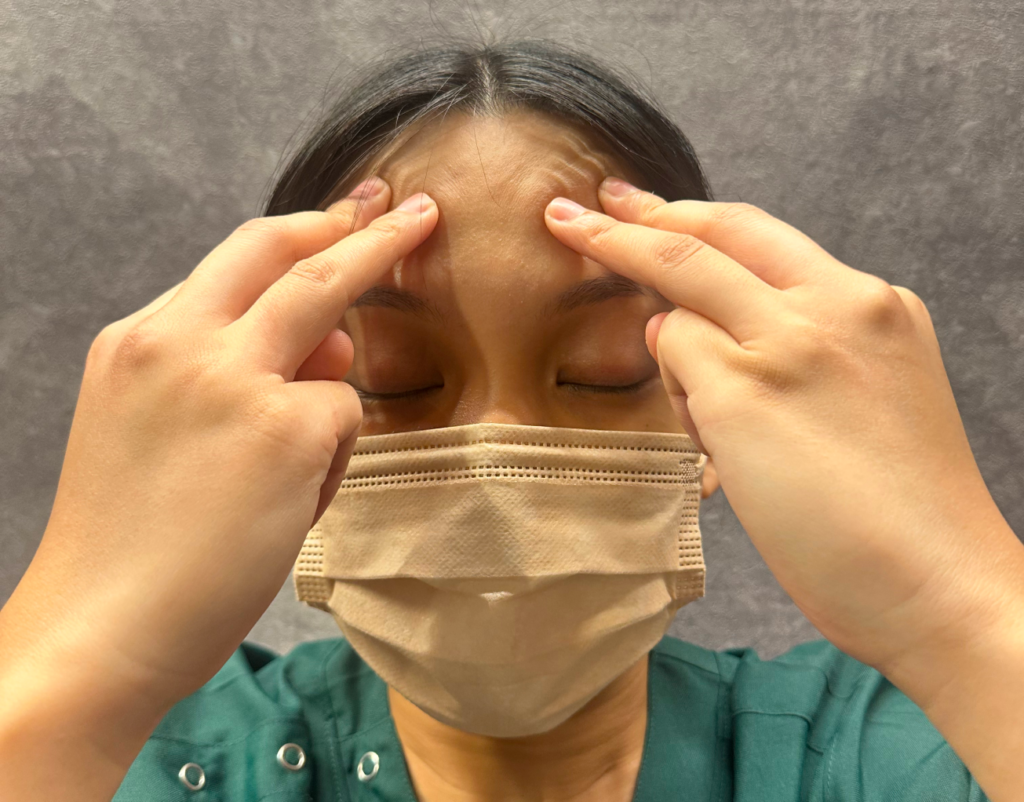 目のたるみを改善する前頭筋の揉みほぐしを行う女性