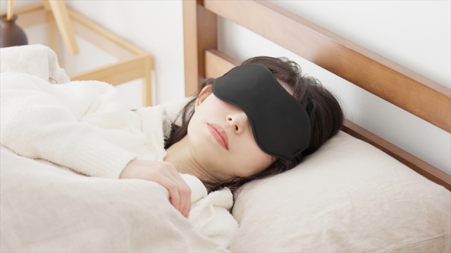 目のたるみを改善するためアイマスクをつけて寝る女性