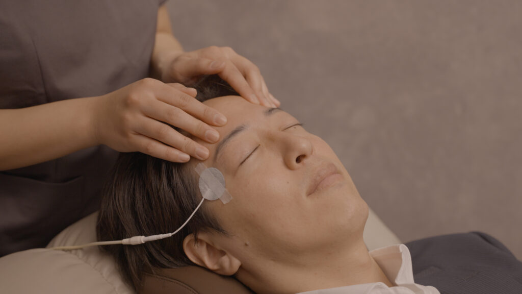 前頭筋の揉みほぐしを受ける男性