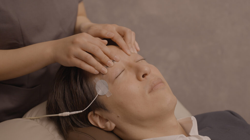 目の痛みを和らげるため揉みほぐしを受ける男性