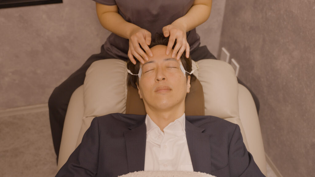 目の痙攣を緩和するため、ANDBLINQで施術を受ける男性