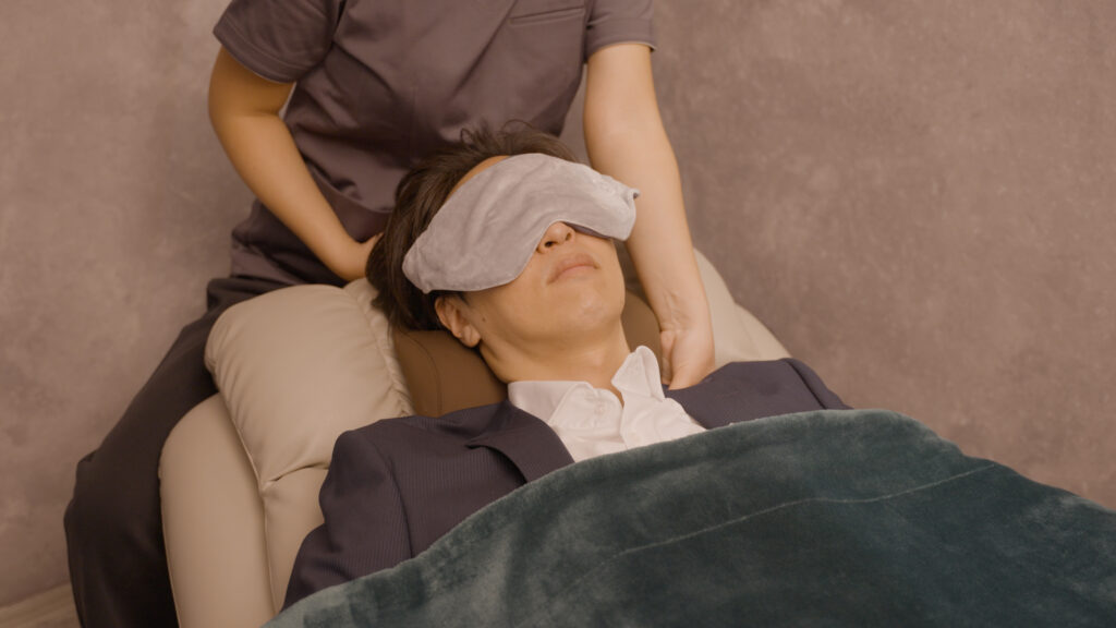 目のピクピクを治すために温罨法を受ける男性