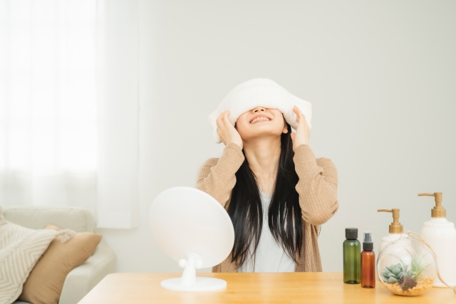 目の痛みを和らげるため、温罨法を試す女性