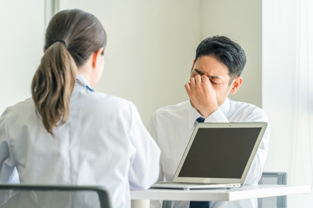 目の痛みを医者に相談する男性